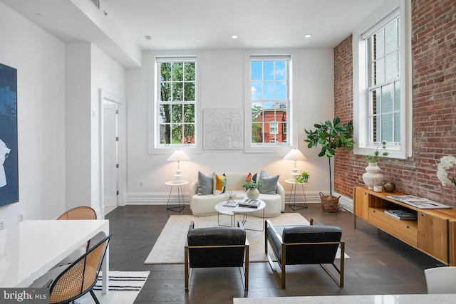 living area featuring dark wood-style floors, baseboards, brick wall, and recessed lighting