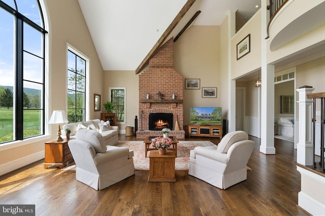 living room featuring high vaulted ceiling, a brick fireplace, dark wood-type flooring, and baseboards
