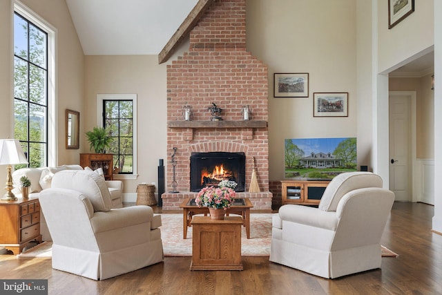living room featuring high vaulted ceiling, a brick fireplace, wood finished floors, and plenty of natural light