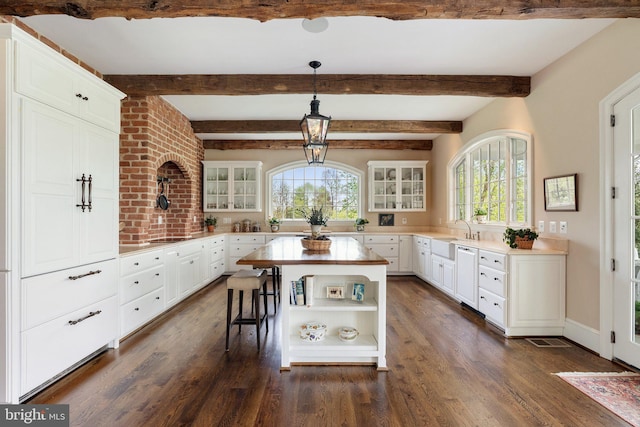 kitchen featuring dishwashing machine, open shelves, dark wood-style flooring, glass insert cabinets, and beam ceiling