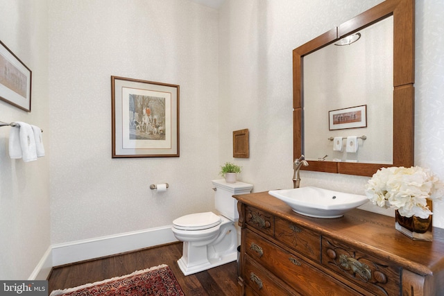 bathroom with wood finished floors, baseboards, toilet, and vanity