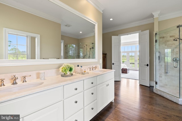 full bath featuring double vanity, a stall shower, wood finished floors, crown molding, and recessed lighting