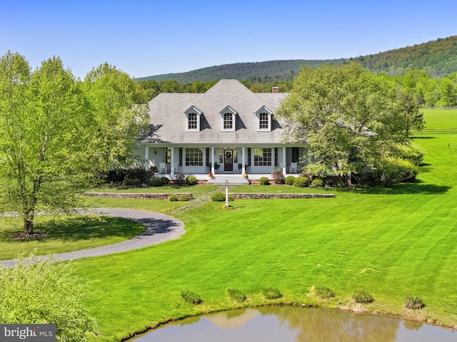 cape cod home with covered porch, a chimney, and a front yard