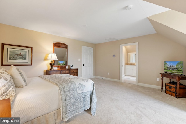 bedroom with light carpet, baseboards, lofted ceiling, and connected bathroom