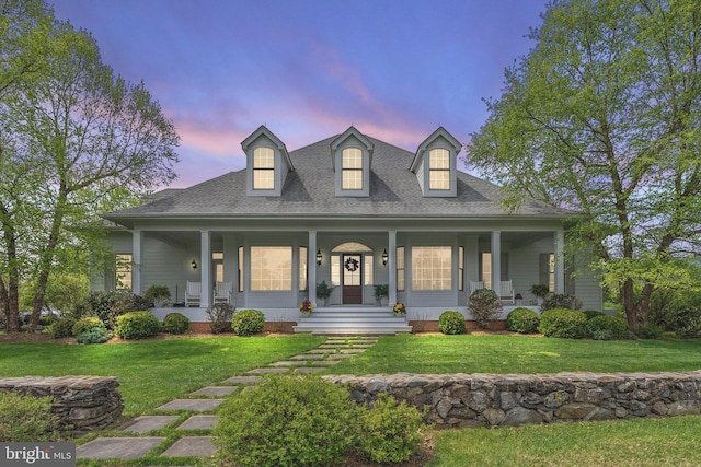 view of front of house featuring a porch, a lawn, and a shingled roof
