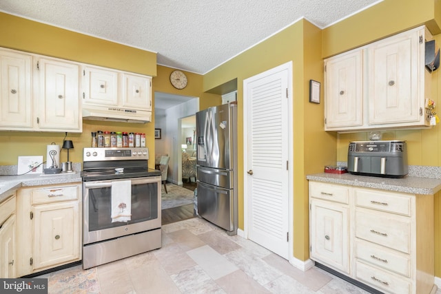 kitchen featuring stainless steel appliances, under cabinet range hood, light countertops, baseboards, and a textured ceiling