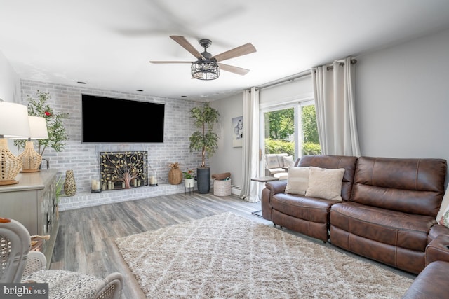 living area with ceiling fan, wood finished floors, and brick wall
