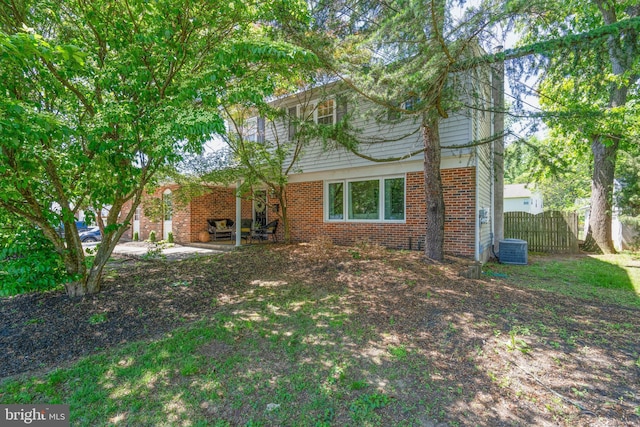 rear view of property with brick siding, cooling unit, and fence