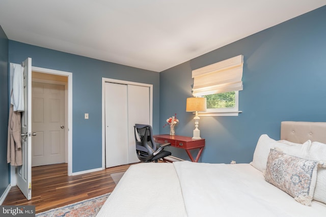bedroom with wood finished floors, baseboards, and a closet