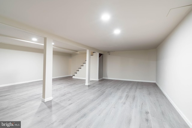 finished below grade area featuring wood finished floors, stairway, recessed lighting, and baseboards