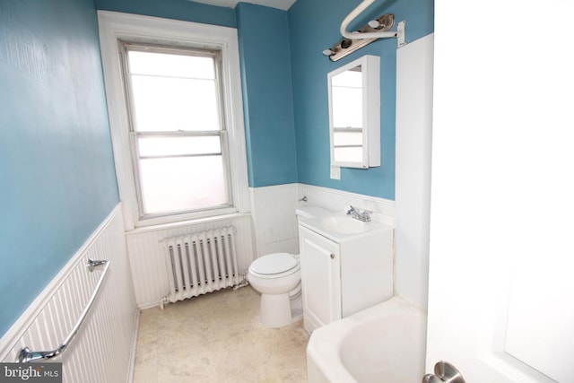 bathroom featuring radiator heating unit, a wainscoted wall, toilet, vanity, and a tub