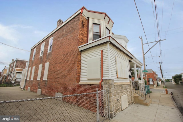 view of side of property featuring fence, brick siding, and a chimney