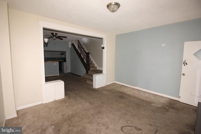 unfurnished living room with stairs, carpet, a ceiling fan, and baseboards