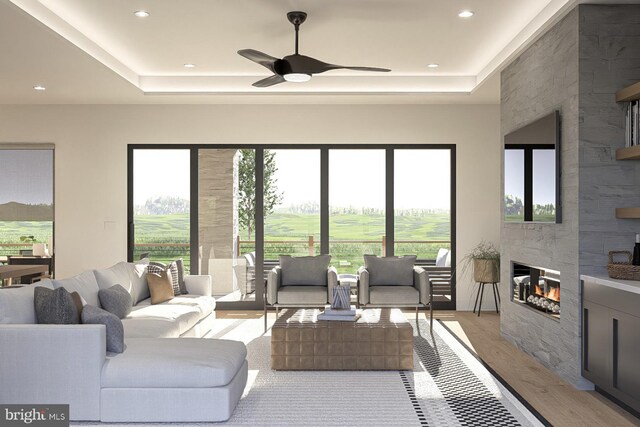 living area with a tray ceiling, light wood-style floors, a ceiling fan, a fireplace, and recessed lighting