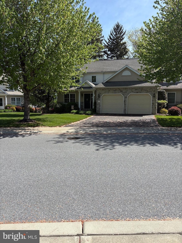 view of front facade with a garage, asphalt driveway, a front lawn, and stone siding