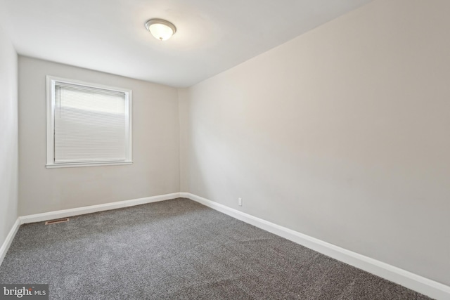 carpeted empty room featuring baseboards