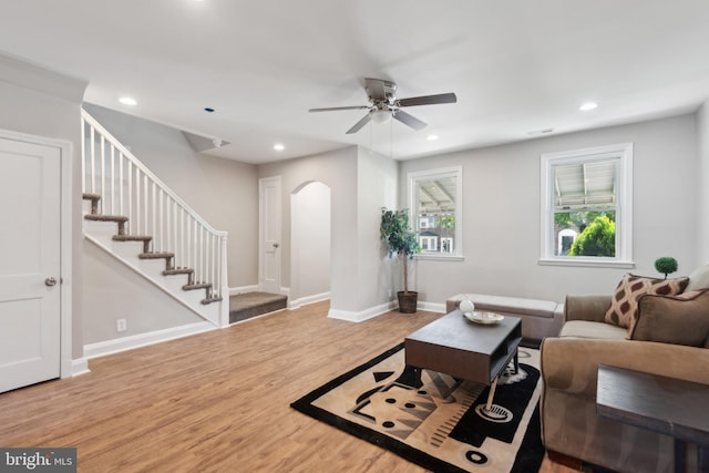 living room featuring arched walkways, ceiling fan, wood finished floors, recessed lighting, and stairs