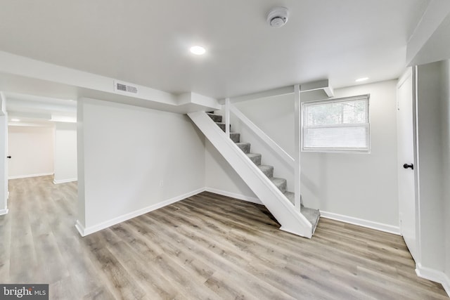 below grade area featuring wood finished floors, stairs, baseboards, and recessed lighting
