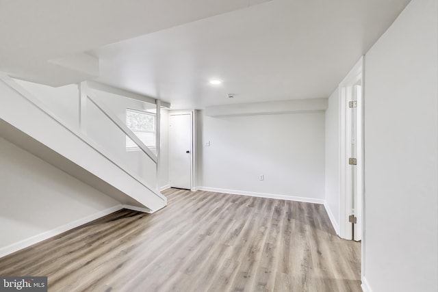 basement with light wood-style floors, baseboards, and stairs