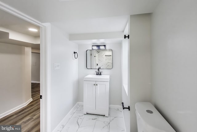bathroom featuring baseboards, vanity, toilet, marble look tiles, and recessed lighting