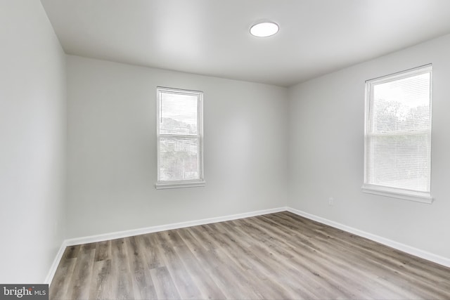 unfurnished room with plenty of natural light, wood finished floors, and baseboards