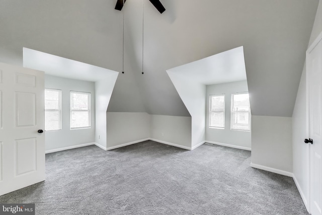 additional living space featuring carpet flooring, healthy amount of natural light, baseboards, lofted ceiling, and ceiling fan