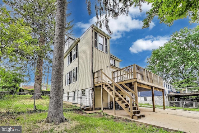 rear view of property with a deck, fence, stairway, driveway, and a patio
