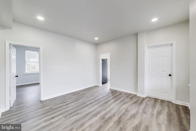 empty room with wood finished floors, recessed lighting, and baseboards