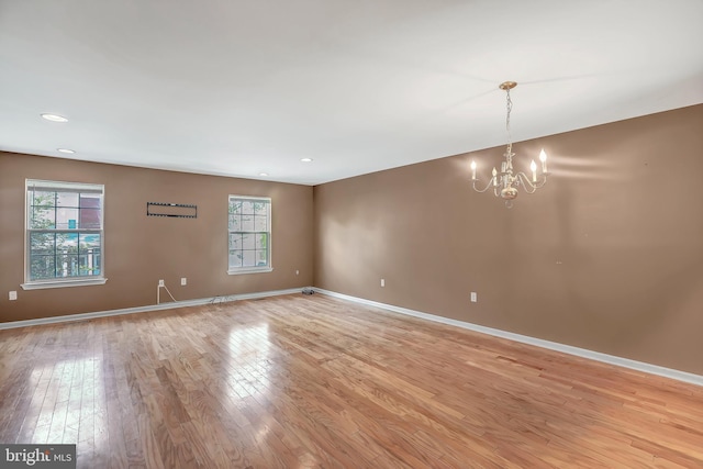 empty room with light wood finished floors, baseboards, a chandelier, and recessed lighting