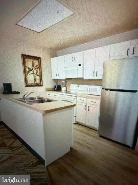 Moseywood Rd, Lake Harmony, PA 18624 - kitchen with white appliances, a peninsula, white cabinets, light countertops, and wood finished floors