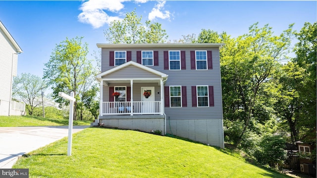 view of front of property with covered porch, a front yard, and concrete driveway