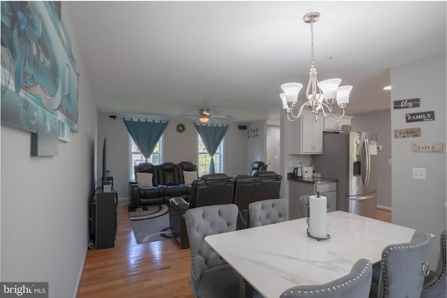 dining room with a ceiling fan, light wood-type flooring, a chandelier, and baseboards