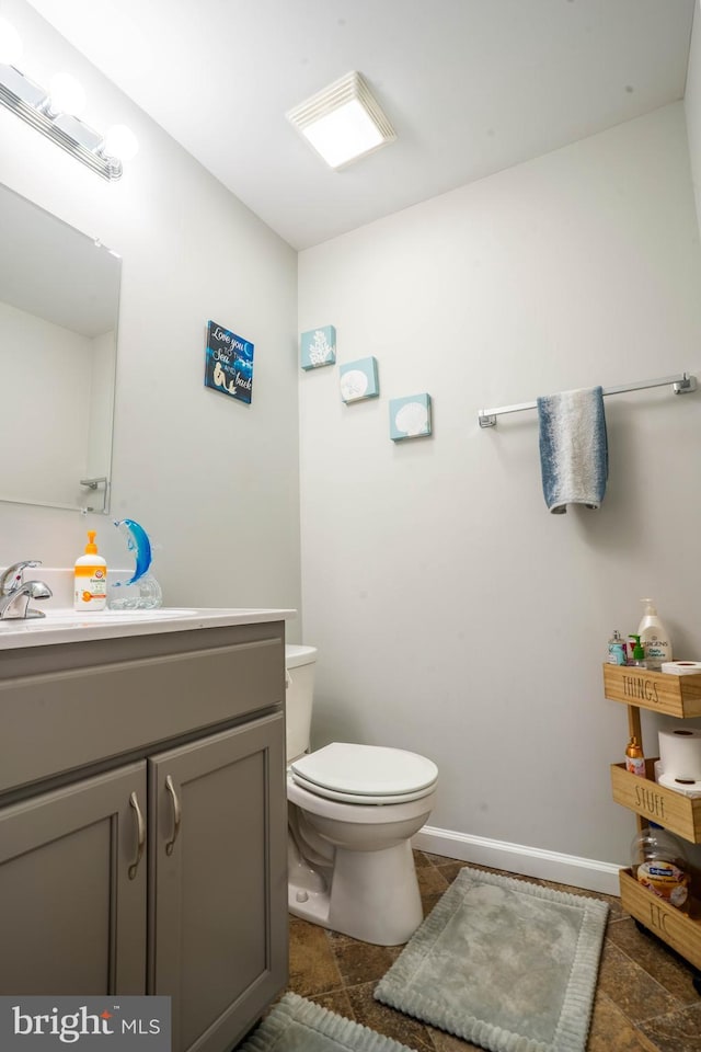 half bathroom featuring toilet, vanity, and baseboards