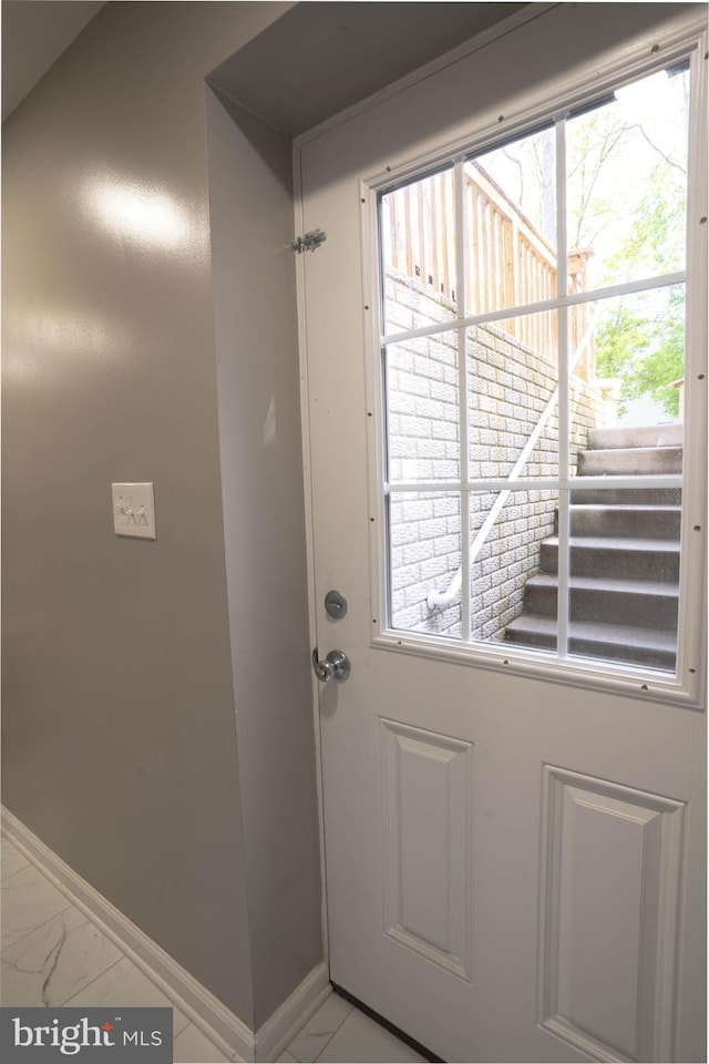 doorway with baseboards, plenty of natural light, and light marble finish flooring