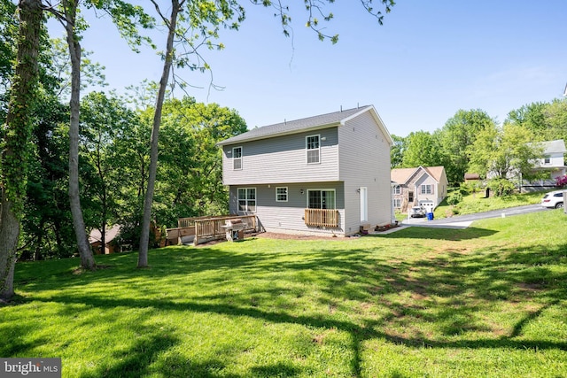 back of property with a wooden deck and a lawn