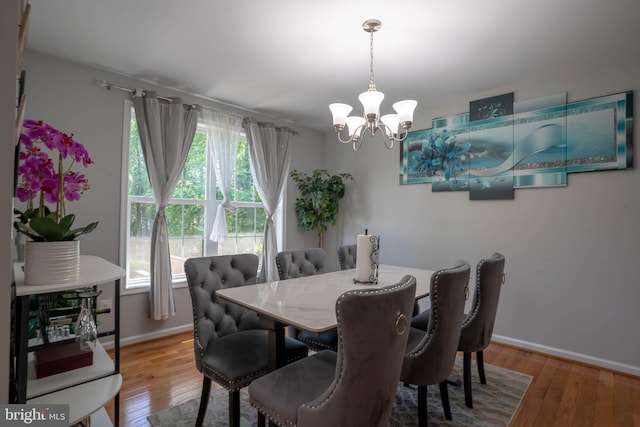 dining room with a chandelier, hardwood / wood-style flooring, and baseboards
