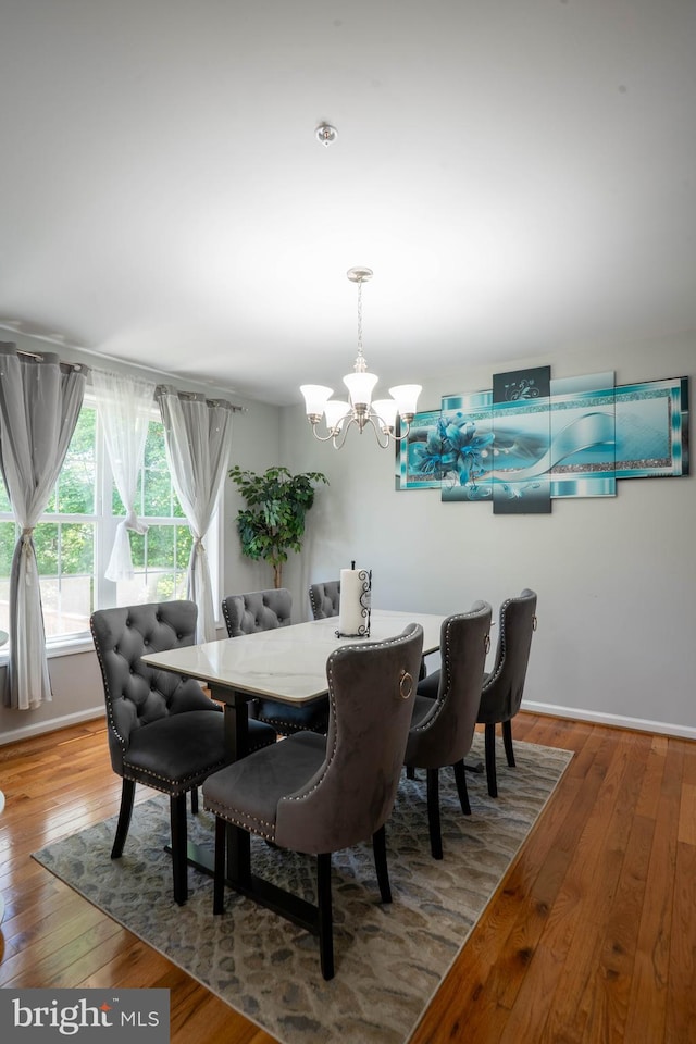 dining room with a chandelier, hardwood / wood-style flooring, and baseboards