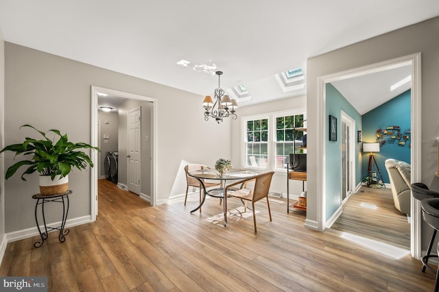 dining area with a chandelier, wood finished floors, independent washer and dryer, and baseboards