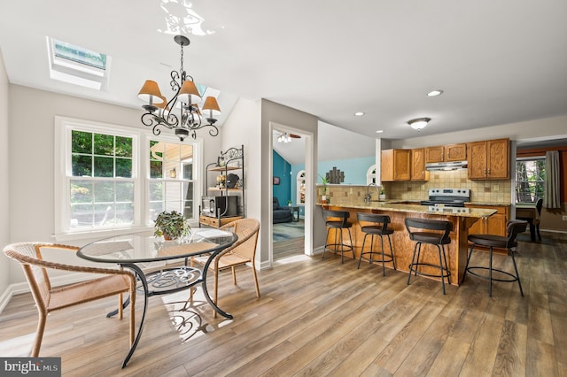 dining space featuring a chandelier, light wood-style floors, a skylight, plenty of natural light, and recessed lighting