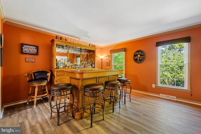 indoor dry bar featuring ornamental molding, wood finished floors, and baseboards