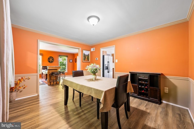 dining space featuring wood finished floors and ornamental molding