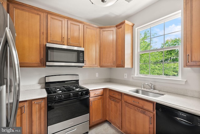 kitchen featuring appliances with stainless steel finishes, a sink, and light countertops