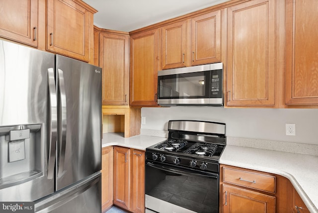 kitchen featuring appliances with stainless steel finishes, light stone counters, and brown cabinetry