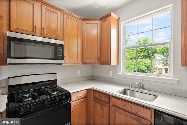 kitchen with black appliances, a sink, plenty of natural light, and light countertops