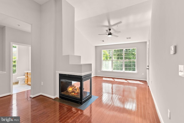 unfurnished living room featuring healthy amount of natural light, wood-type flooring, ceiling fan, and baseboards