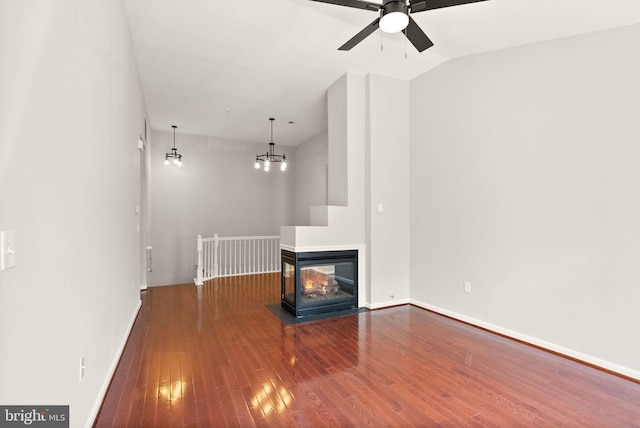 unfurnished living room featuring hardwood / wood-style flooring, a ceiling fan, baseboards, and a multi sided fireplace