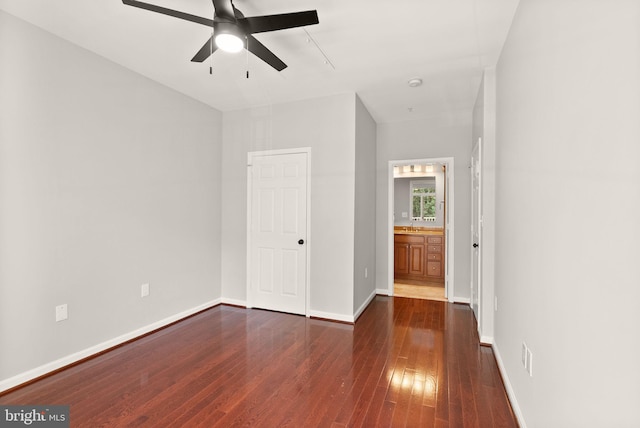 unfurnished bedroom featuring dark wood finished floors, baseboards, a ceiling fan, and ensuite bathroom