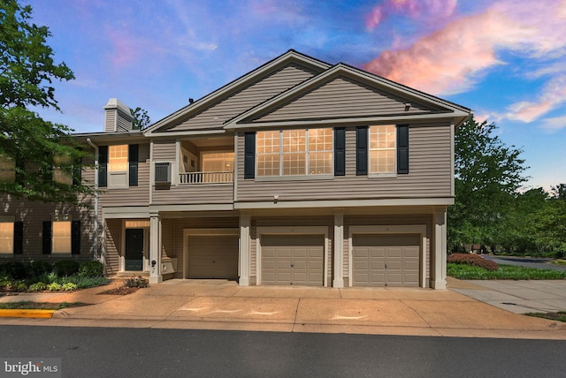 view of front facade featuring an attached garage, driveway, a chimney, and a balcony