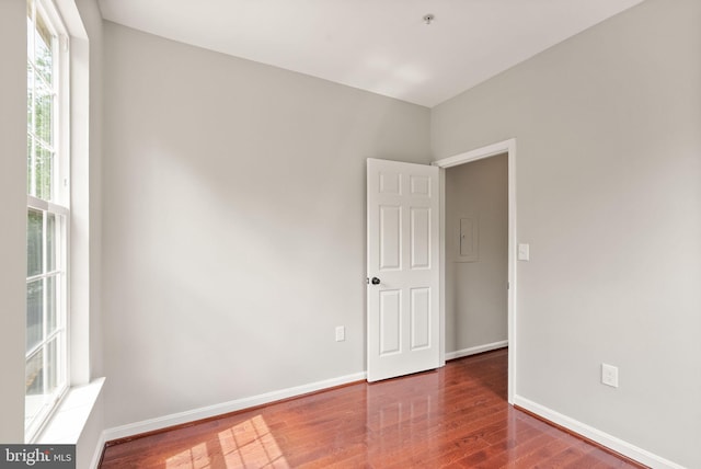 unfurnished room featuring wood finished floors, baseboards, and a pendent fire sprinkler