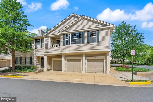 view of property featuring a garage, a chimney, driveway, and a balcony
